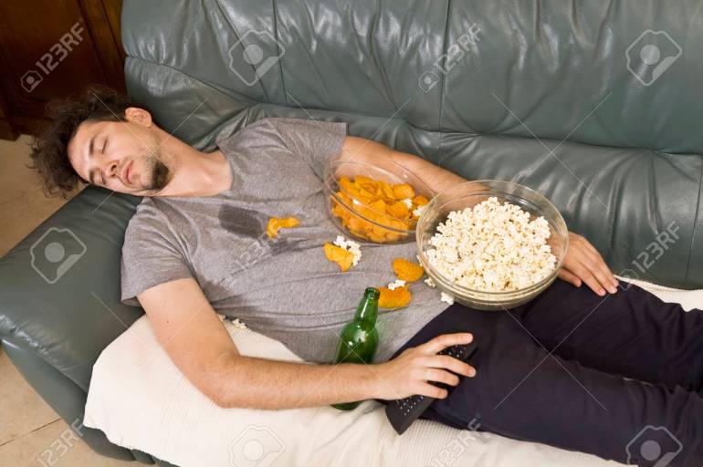 Sleeping yong man relax after work, beer and popcorn and chips